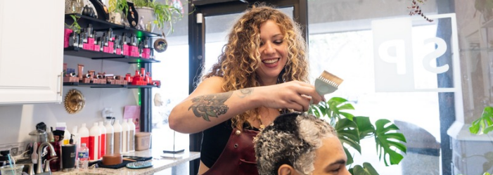 Hairstylist applying hair color with a brush to a client in her salon suite