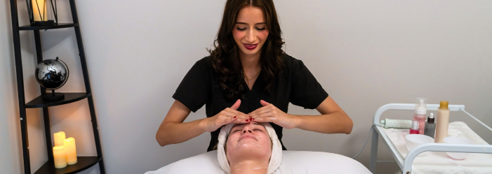 Esthetician giving a client a relaxing facial in a calm treatment room